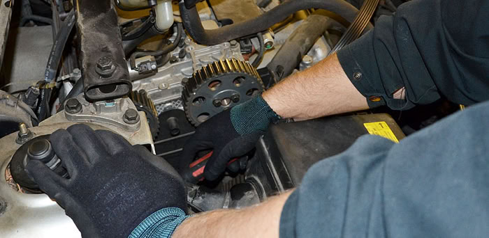 A person wearing gloves working on a car engine.